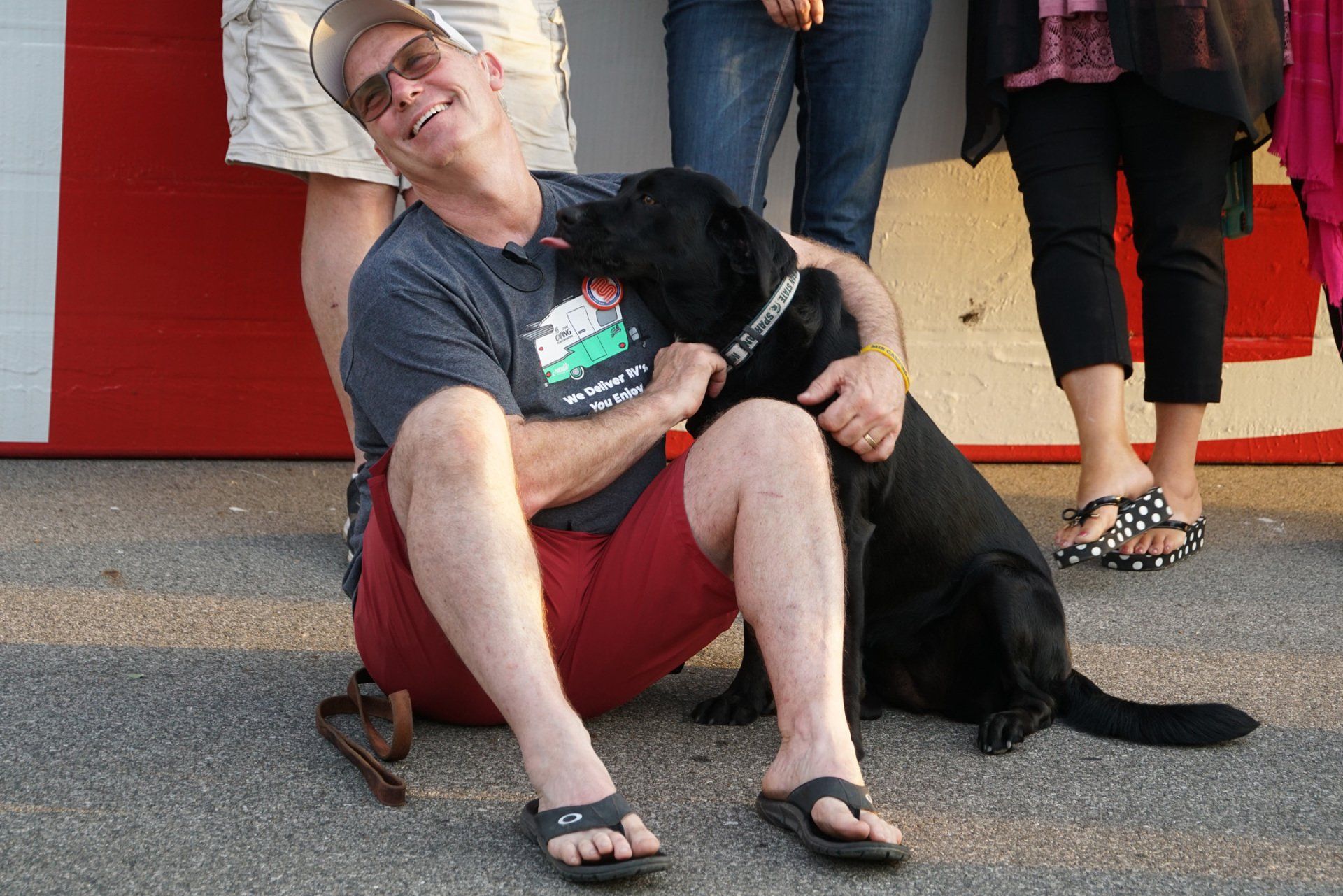 A man kneeling down with a black dog on his lap