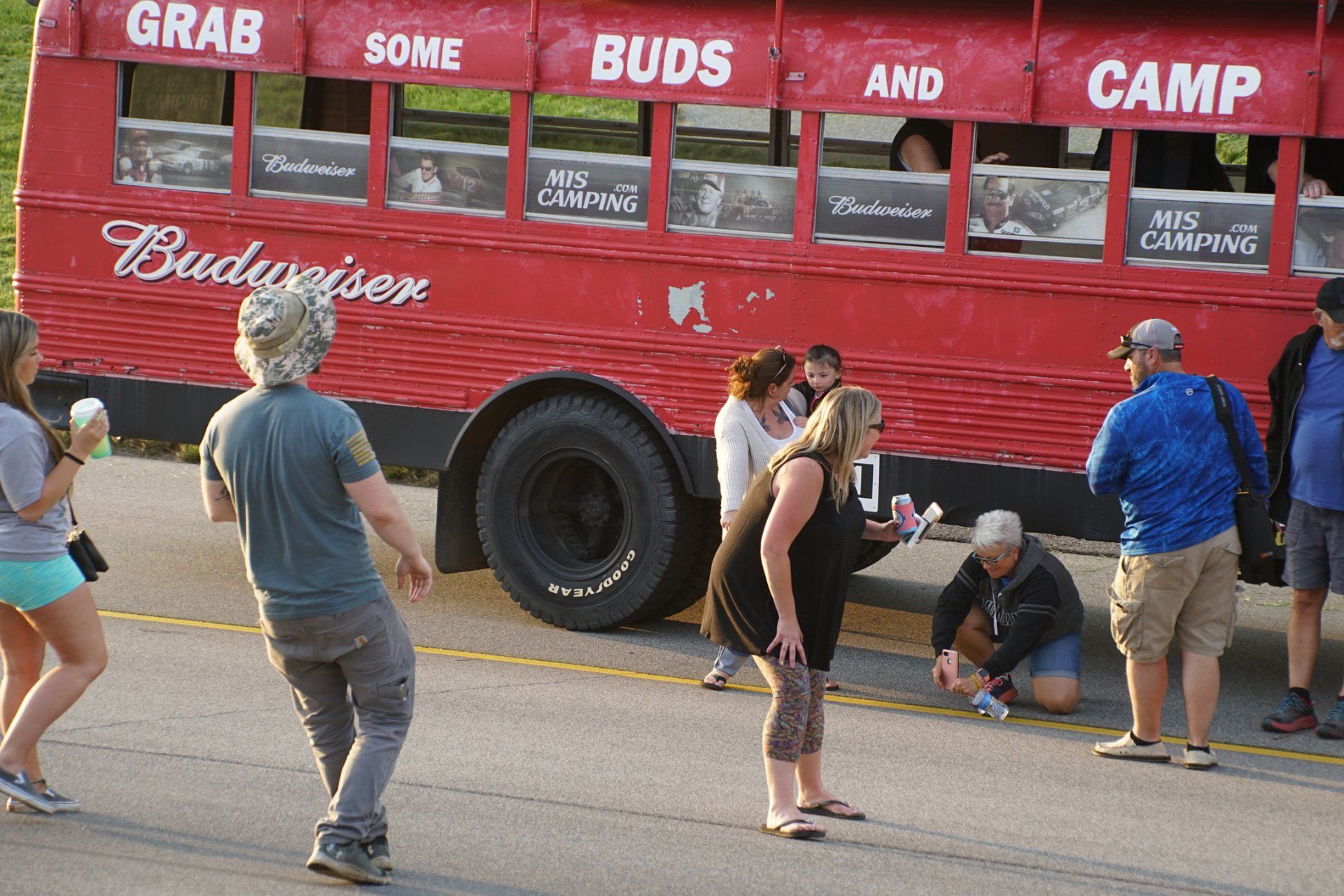 A group of people are standing in front of a budweiser bus