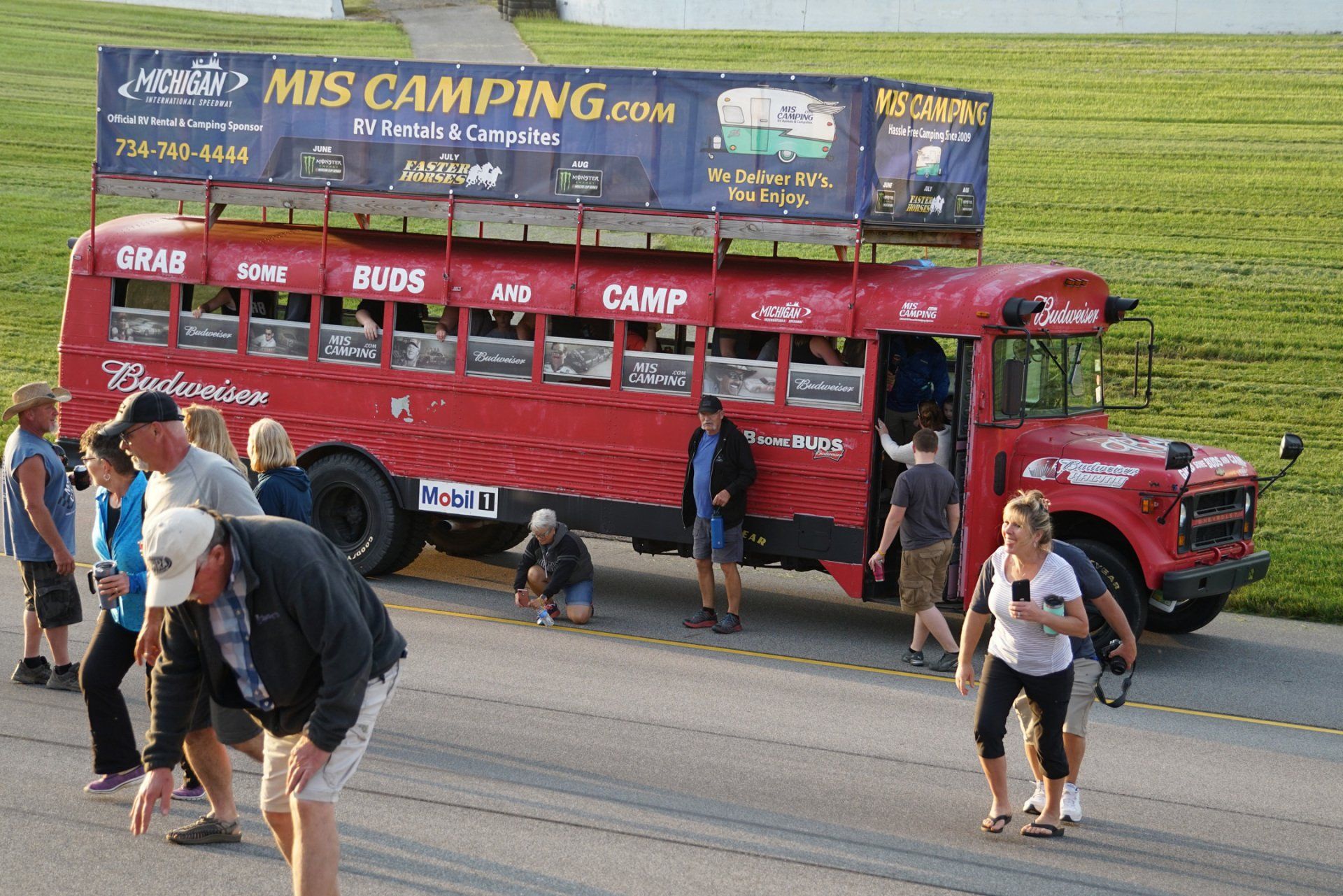 A group of people are walking in front of a bus that says mis camping.com