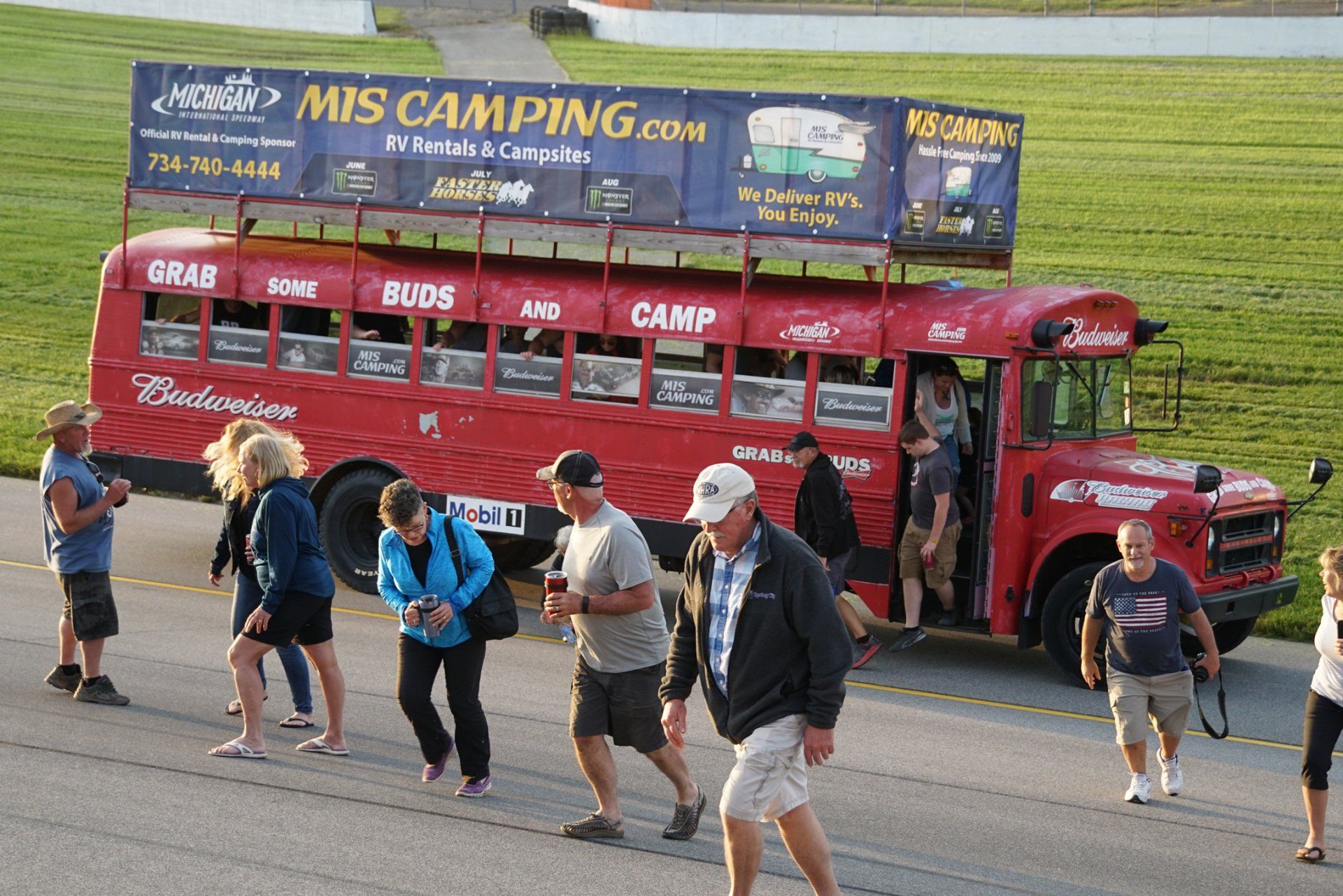 A group of people walking in front of a bus that says mis camping