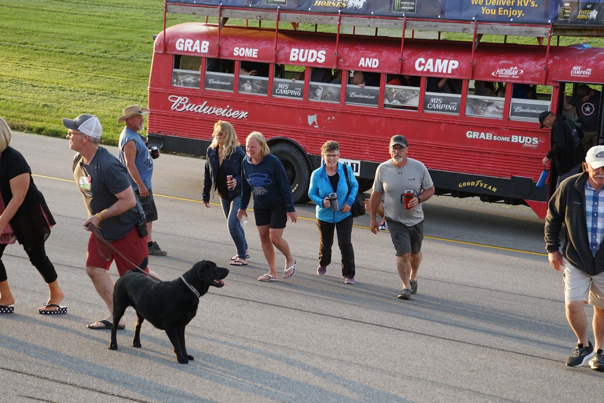 A group of people walking in front of a budweiser bus