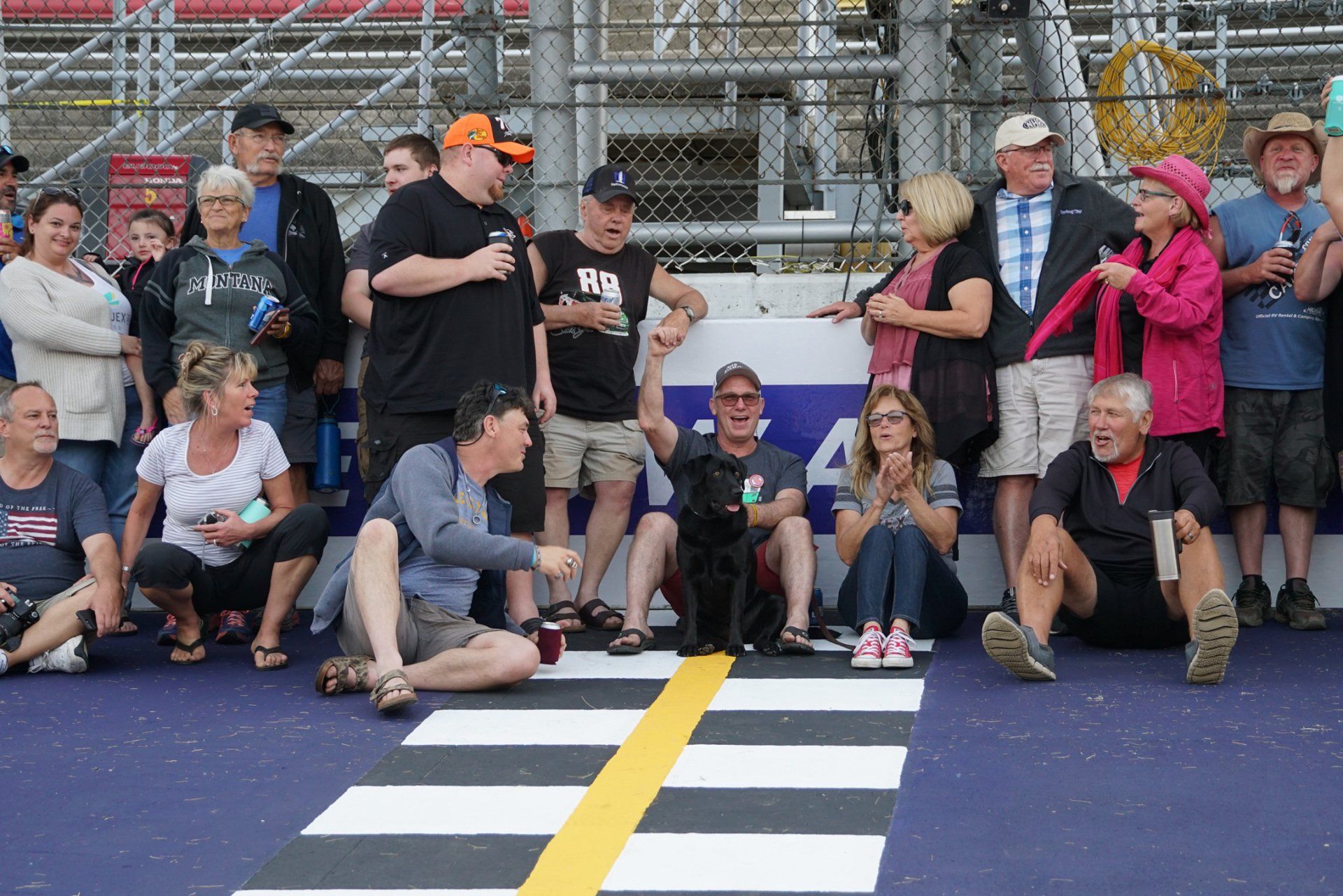 A group of people sitting on the ground watching a race
