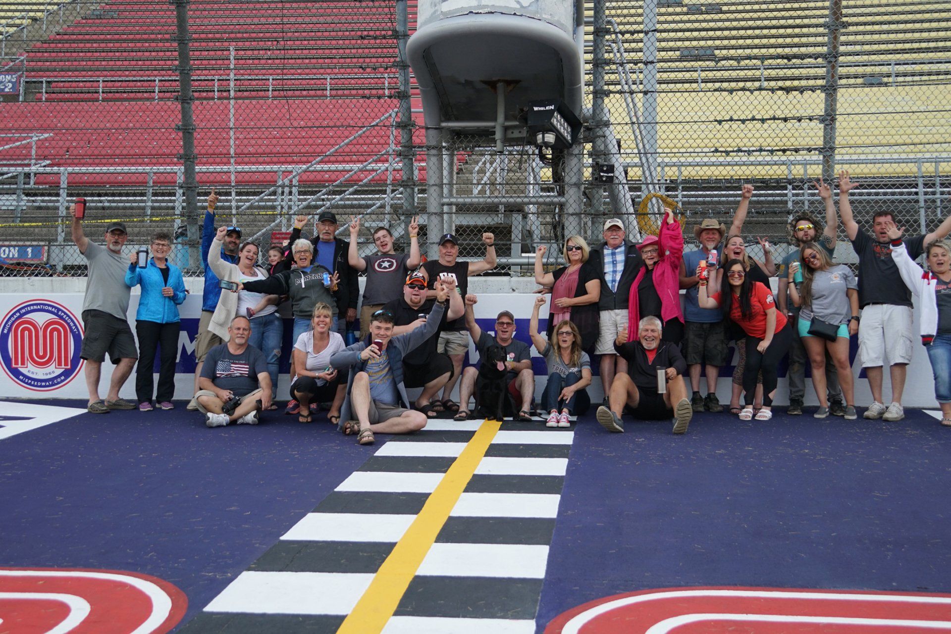 A group of people are posing for a picture on a race track