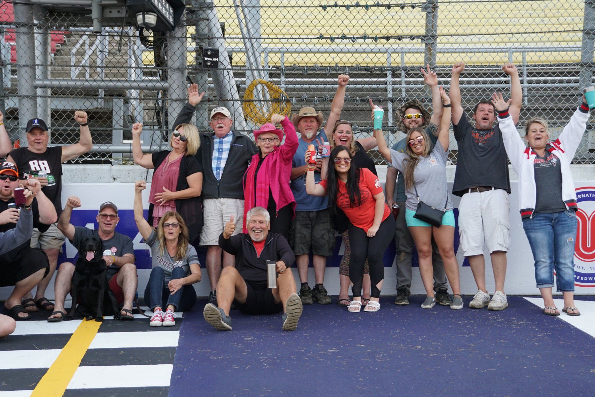 A group of people are posing for a picture on a race track.