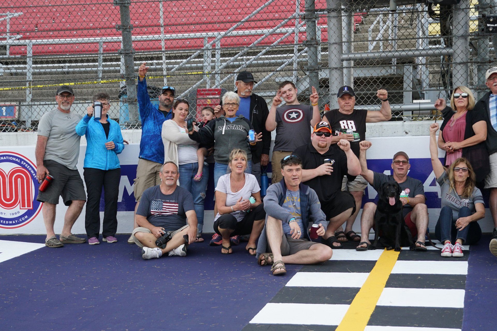 A group of people are posing for a picture on a race track.