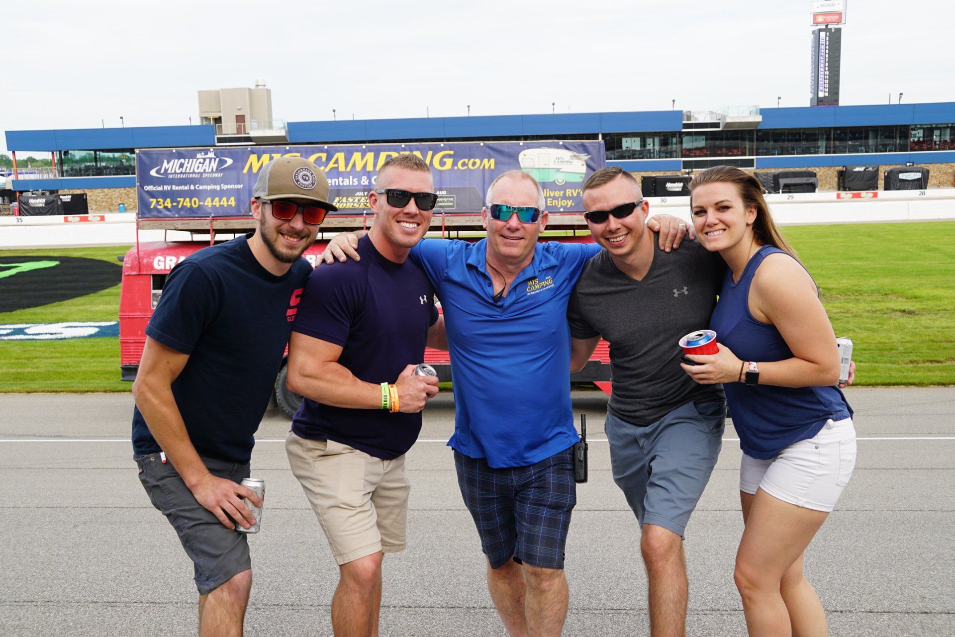 A group of people posing for a picture in front of a race track