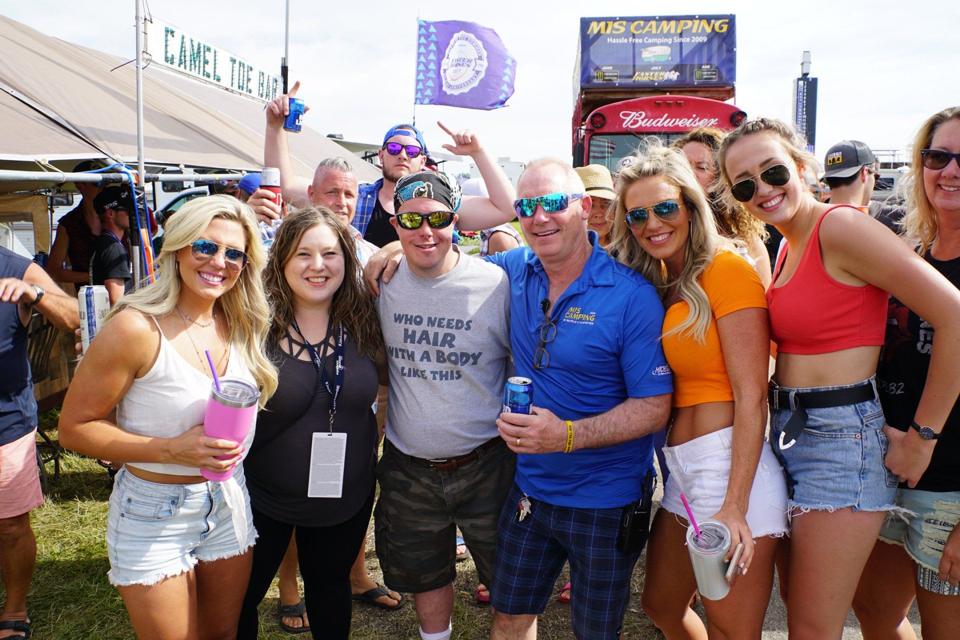 A group of people are posing for a picture in front of a sign that says camel