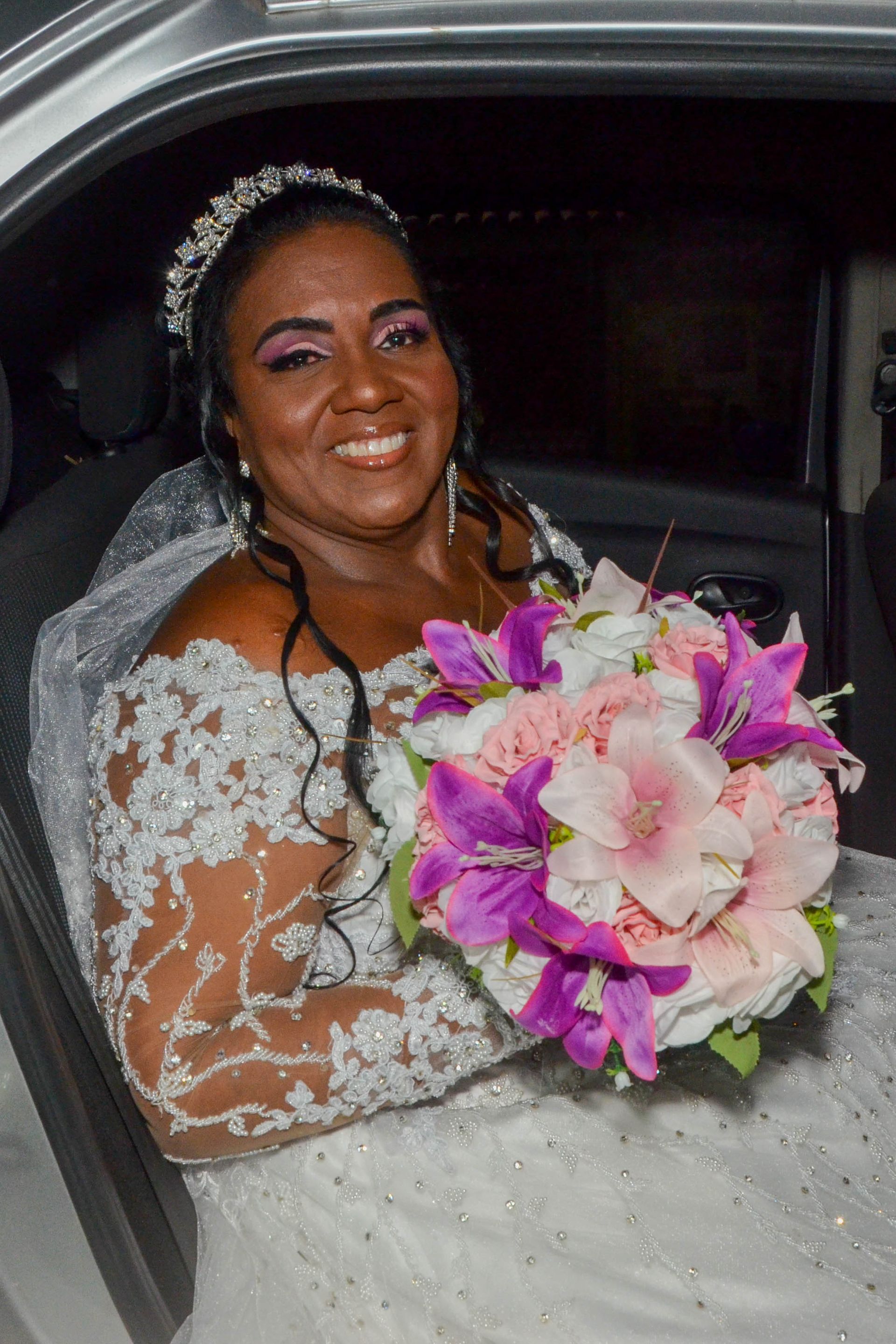 Noiva em vestido de noiva, sorrindo, segurando um buquê de flores.