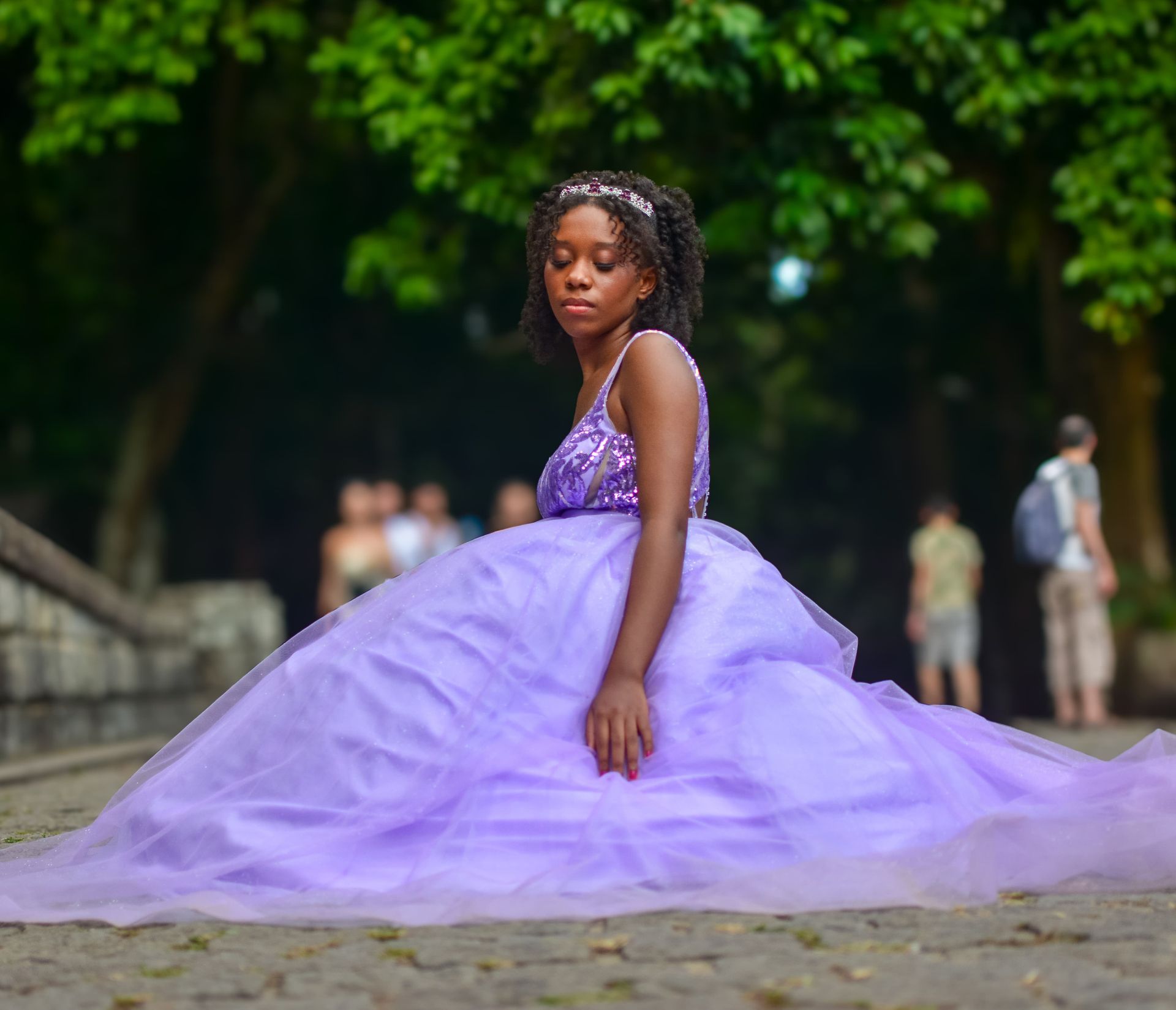 Mulher com vestido lilás ao ar livre com árvores.