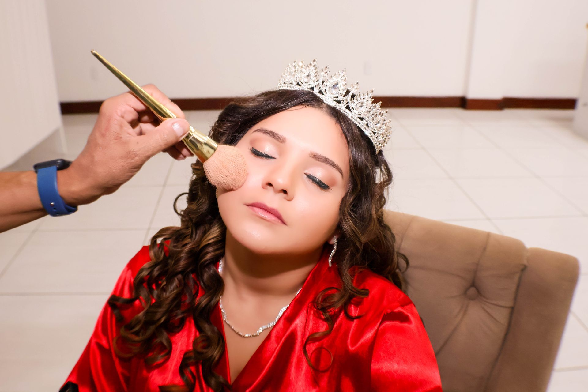 Pessoa com maquiagem aplicada com pincel, usando coroa e túnica vermelha.