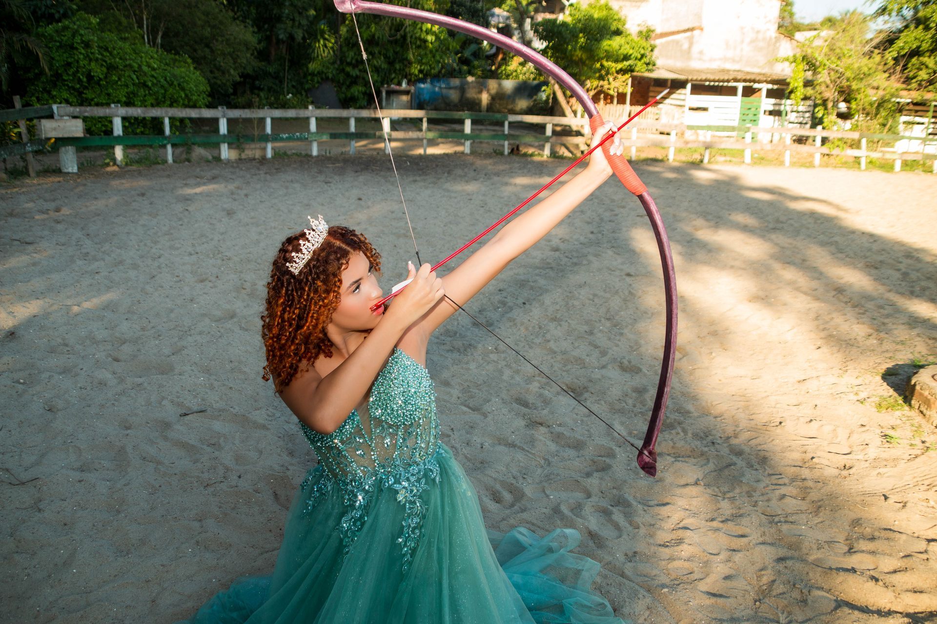 Mulher de vestido azul mira arco e flecha.
