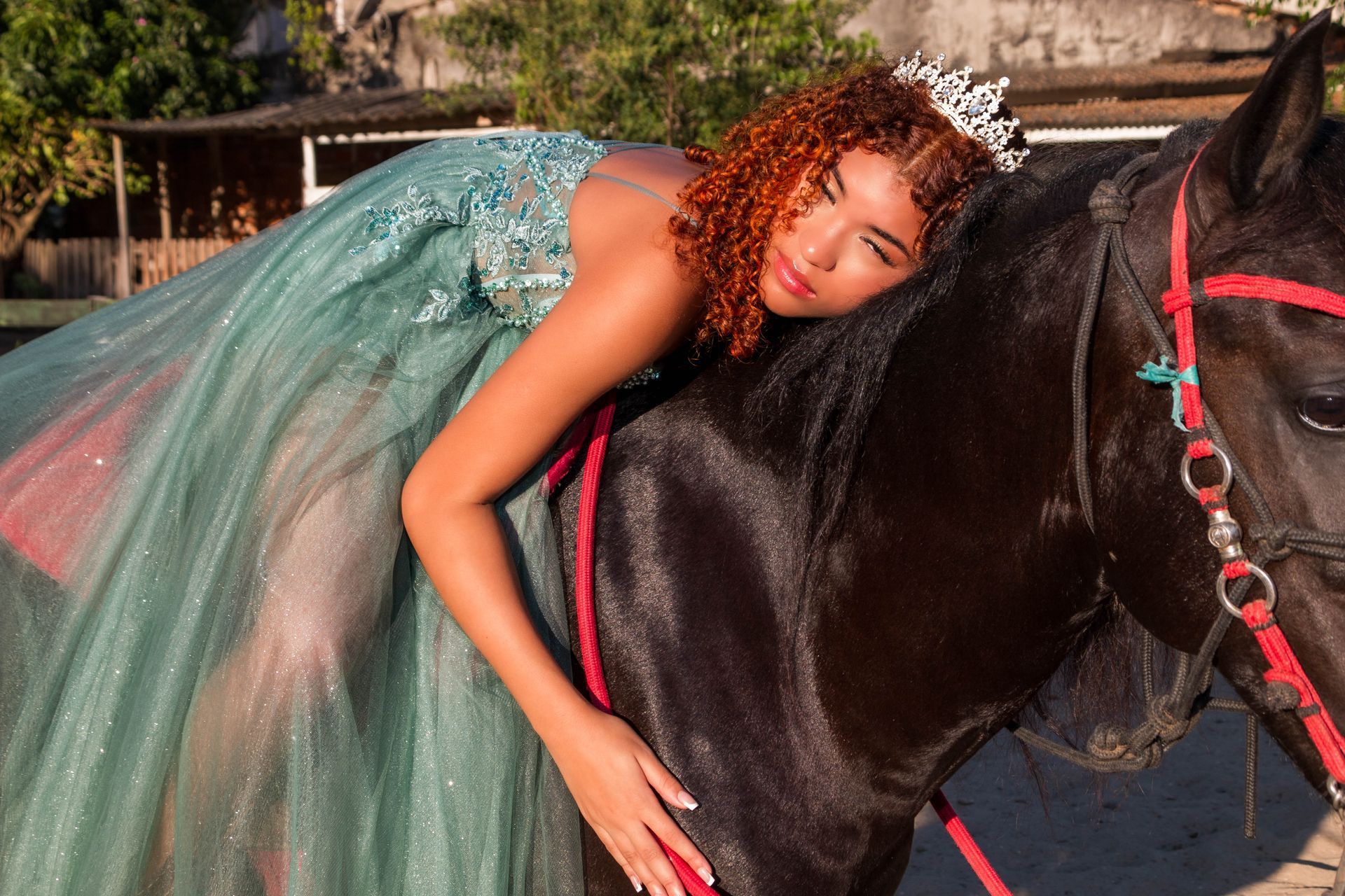 Mulher de vestido e tiara repousa sobre um cavalo preto, com a cabeça apoiada em suas costas.