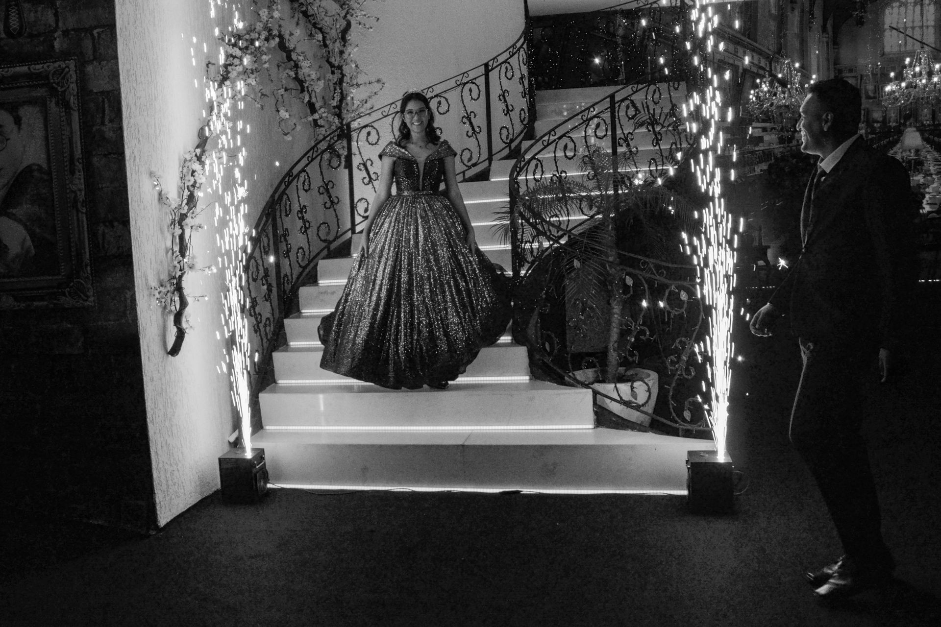 Uma mulher com um vestido brilhante desce uma escada com estrelinhas, enquanto um homem observa.