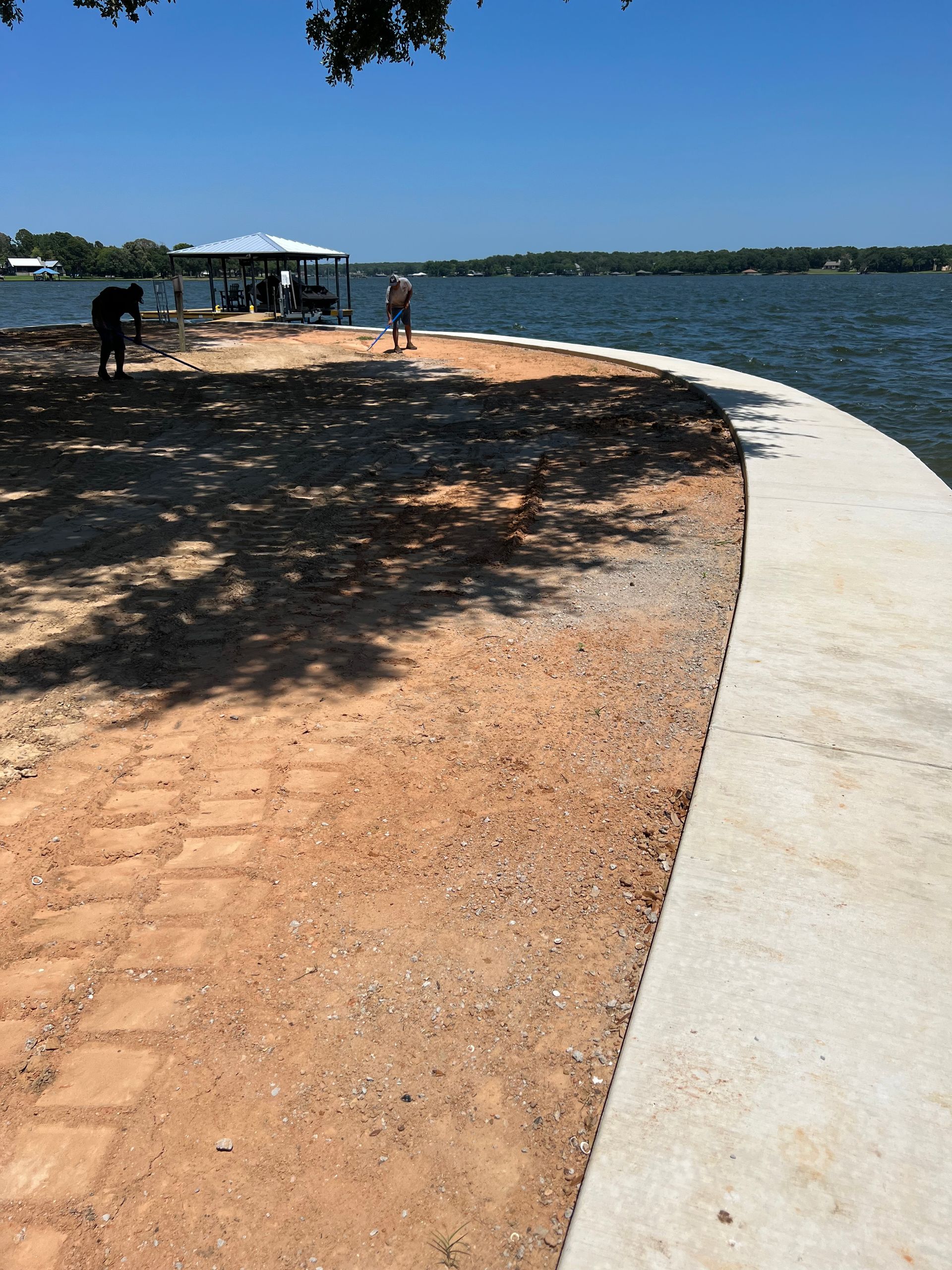A man is working on a concrete walkway next to a body of water.