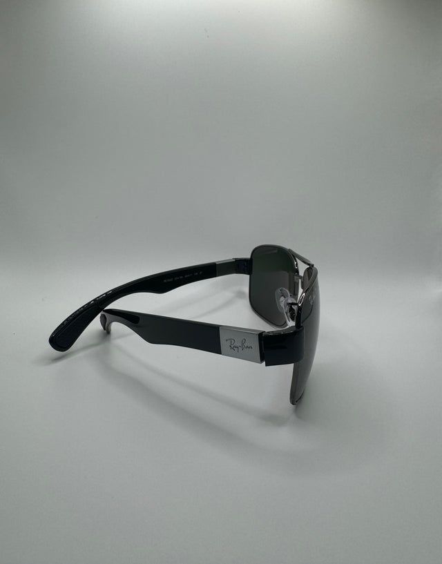 Black Ray-Ban sunglasses on a white background, viewed from the side.