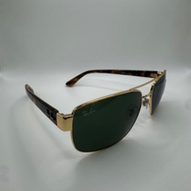 Gold and tortoiseshell Ray-Ban sunglasses with green lenses sit on a white surface.