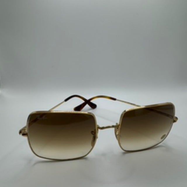 Gold-rimmed sunglasses with gradient brown lenses on a white surface.