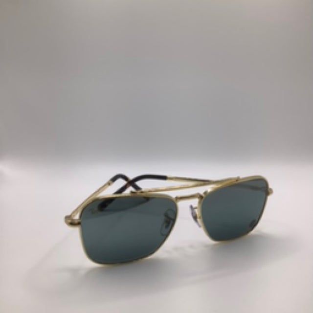 Gold-rimmed aviator sunglasses with dark lenses on a white surface.