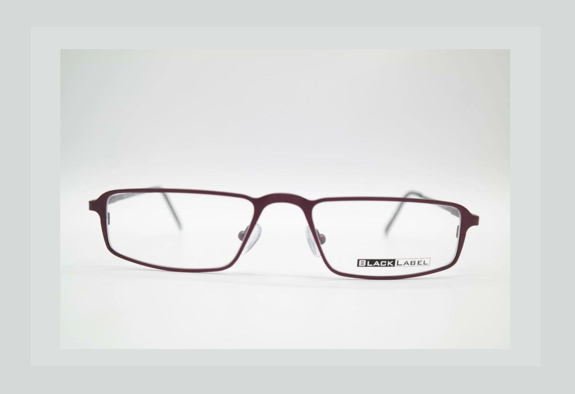 Maroon rectangular eyeglasses on a white surface.