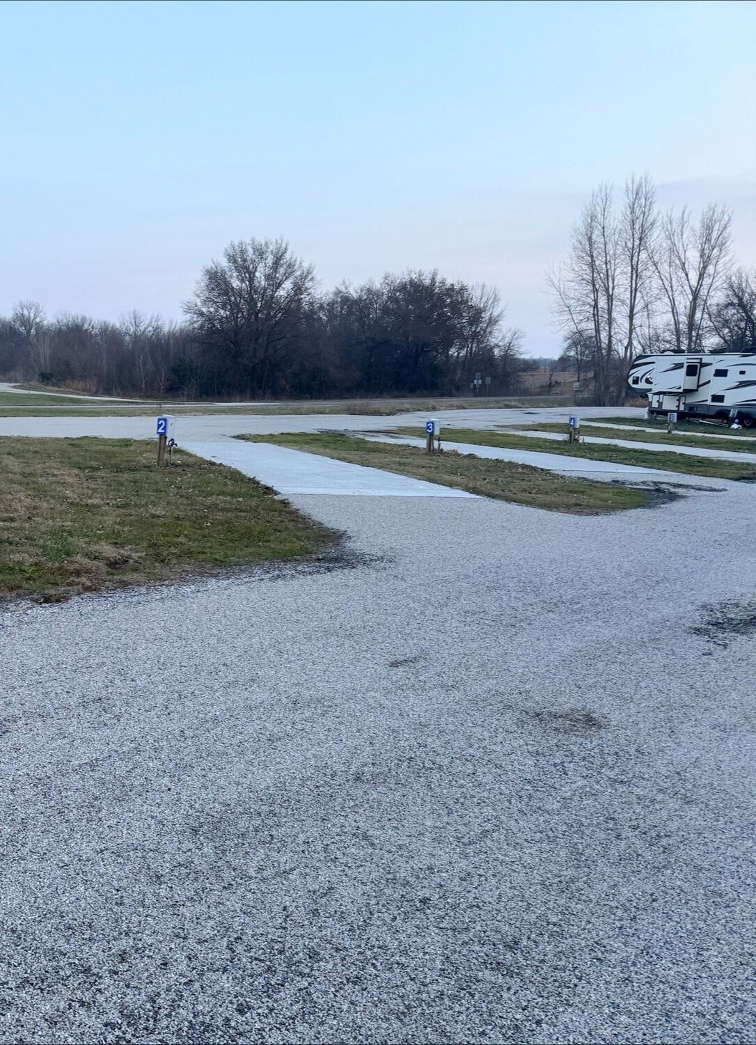 Gravel RV campsites with newly poured concrete pads and numbered hookups at Downey Carriage House RV Park