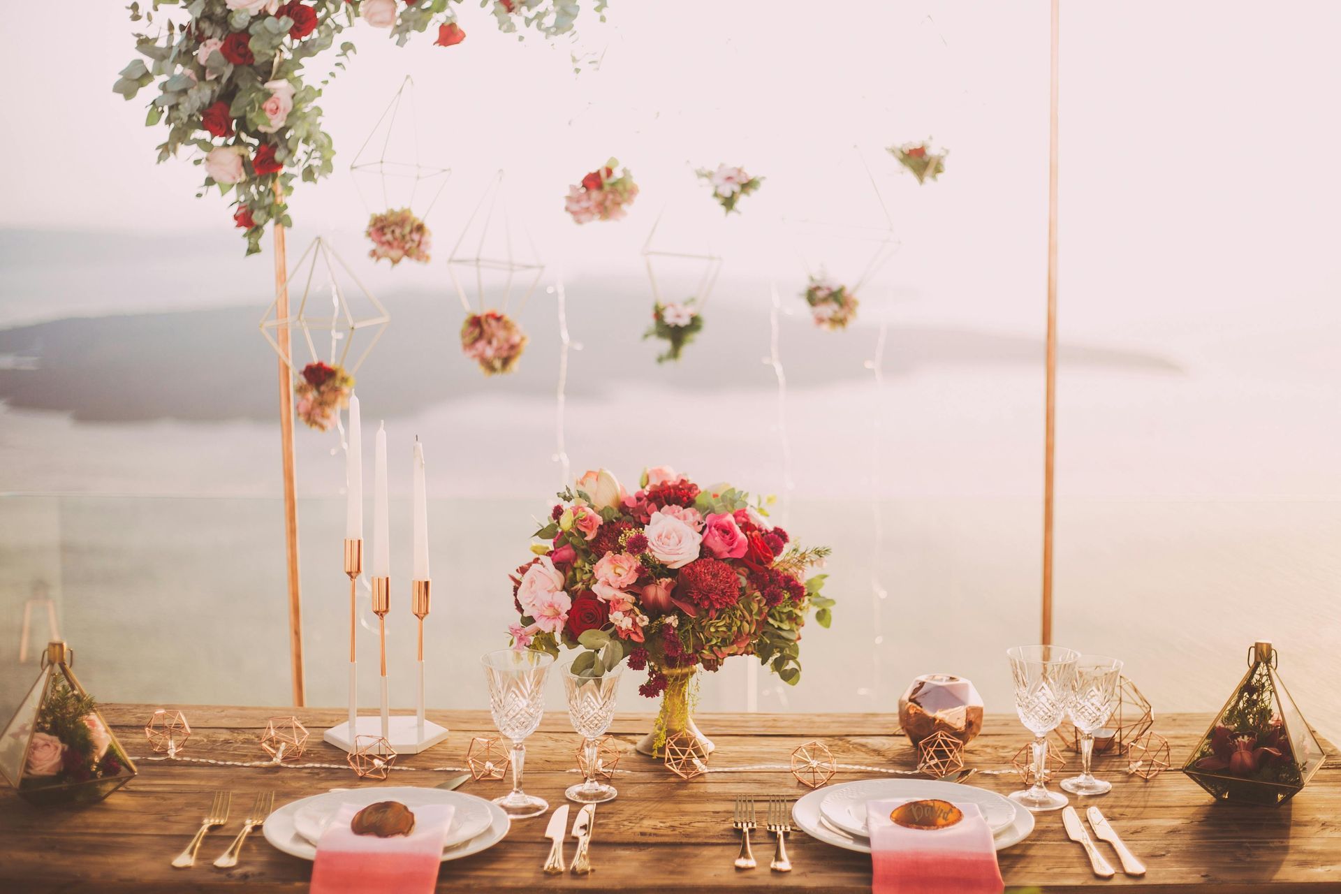Elegant wedding table set outdoors with flowers and candles, overlooking water.