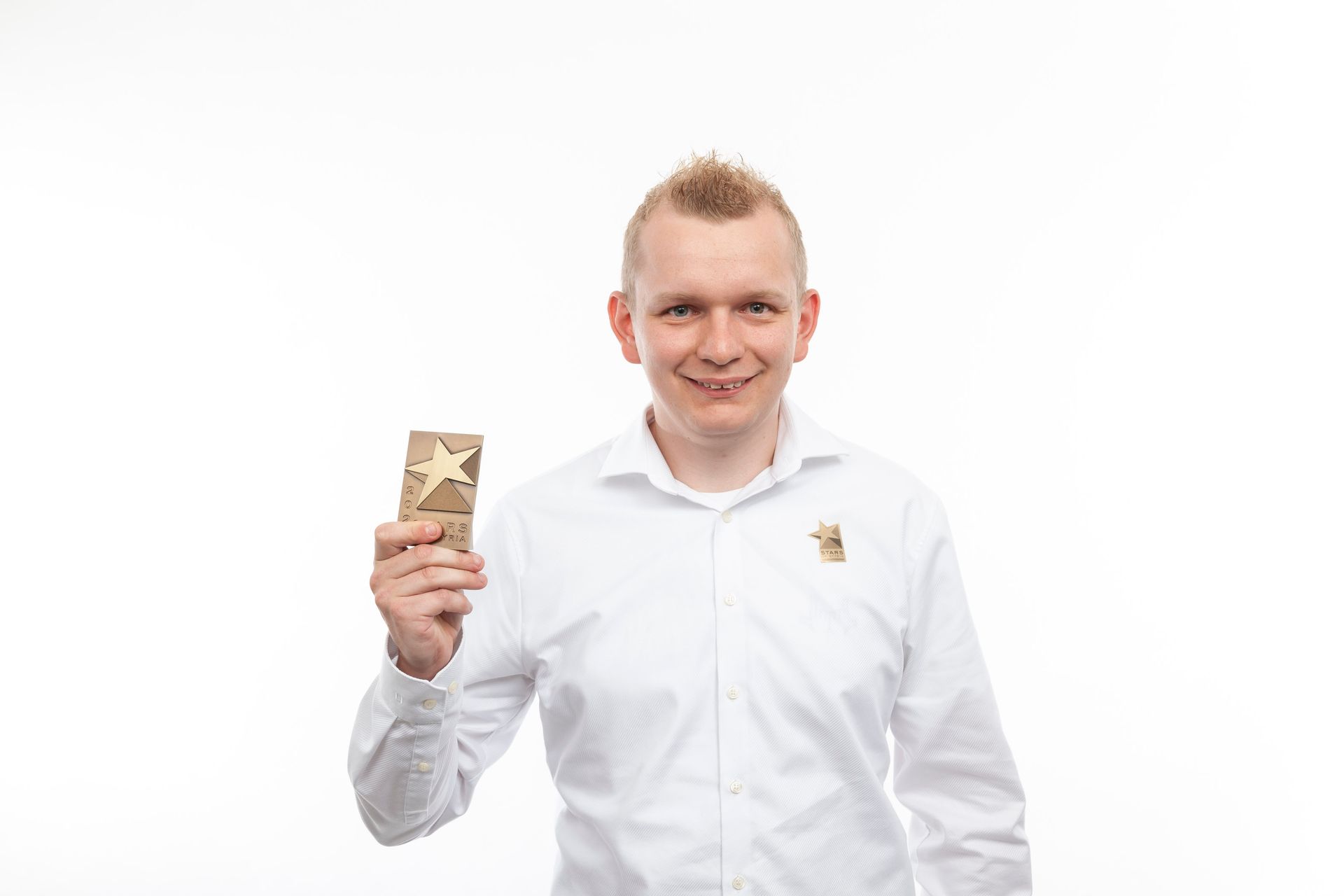 Ein Mann in einem weißen Hemd hält ein Stück Holz mit einem Stern darauf.