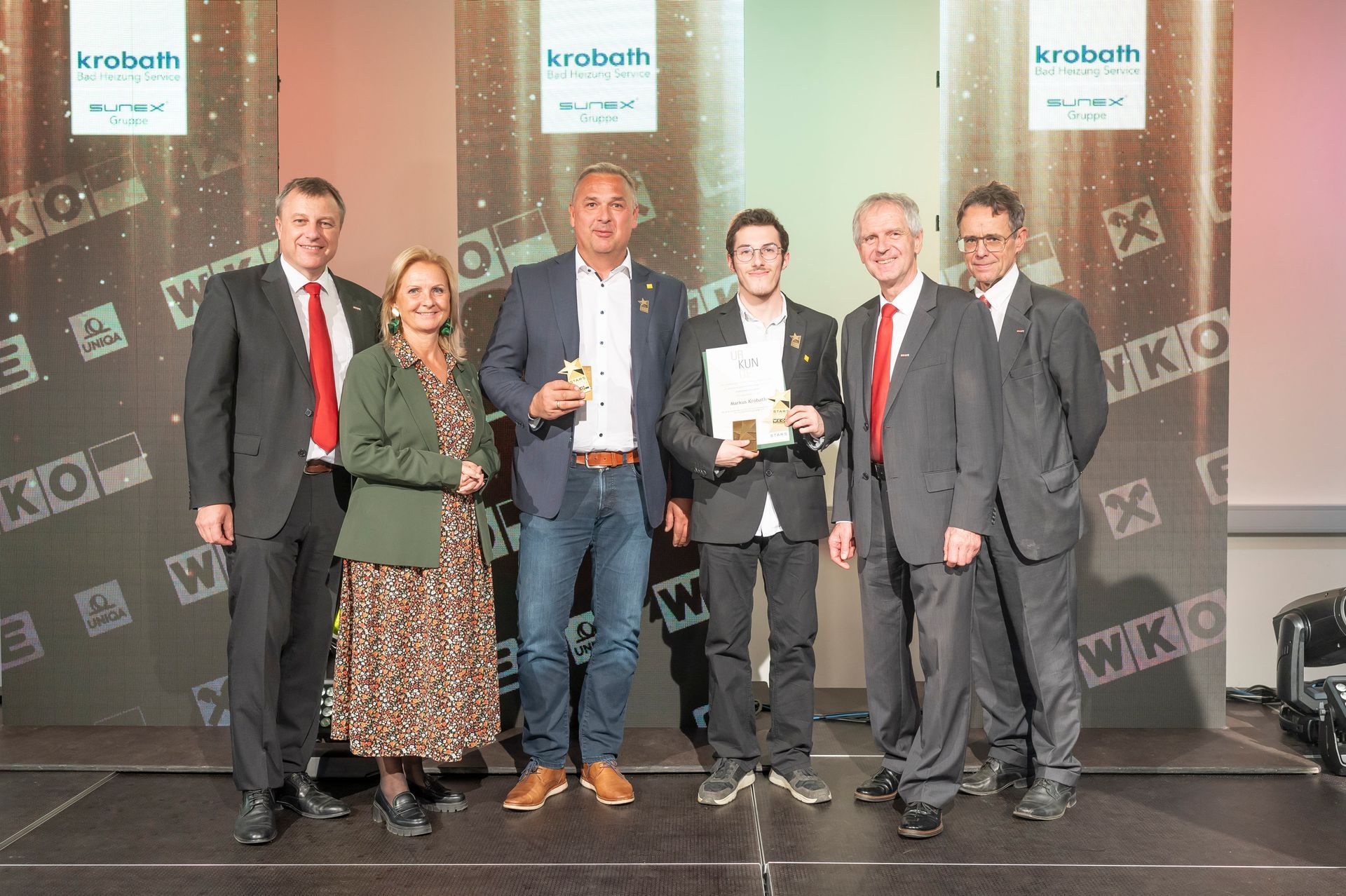 Zwei Männer stehen nebeneinander und halten Auszeichnungen in den Händen.