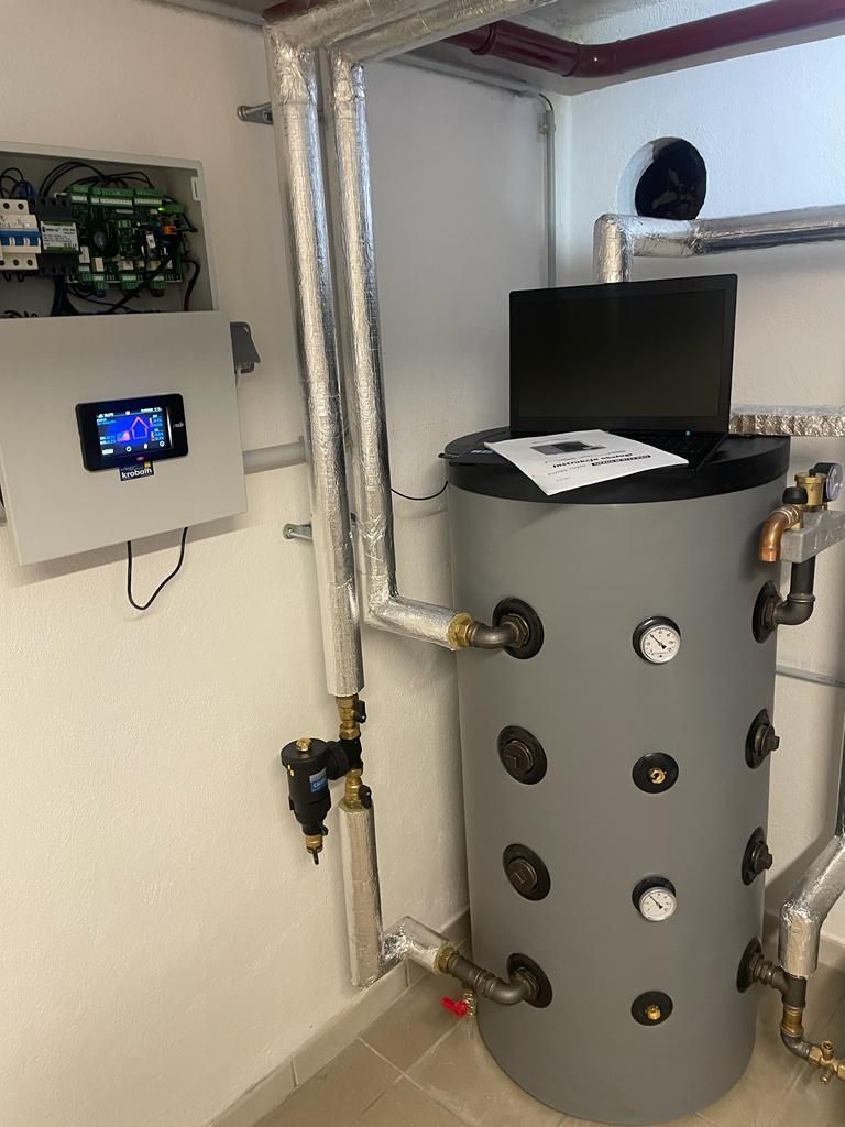 Ein großer grauer Tank steht in einem Raum neben einem Computer.