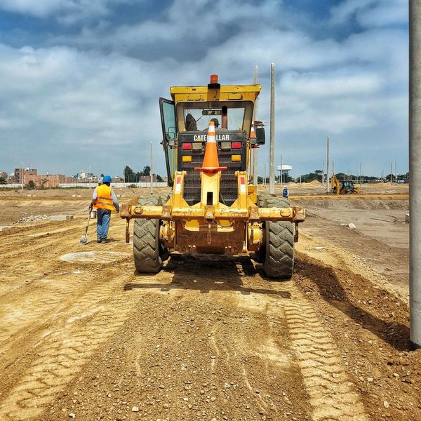 A yellow tractor with a orange cone on top of it