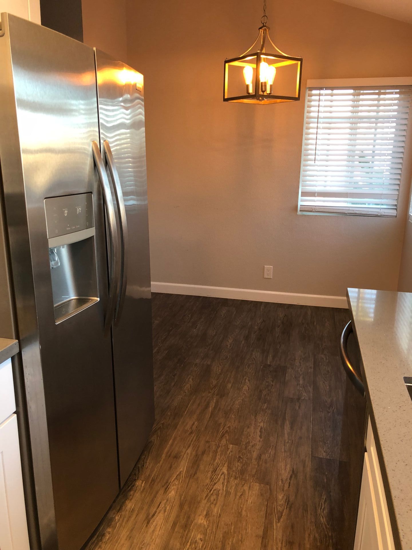 A kitchen with a stainless steel refrigerator and a window.