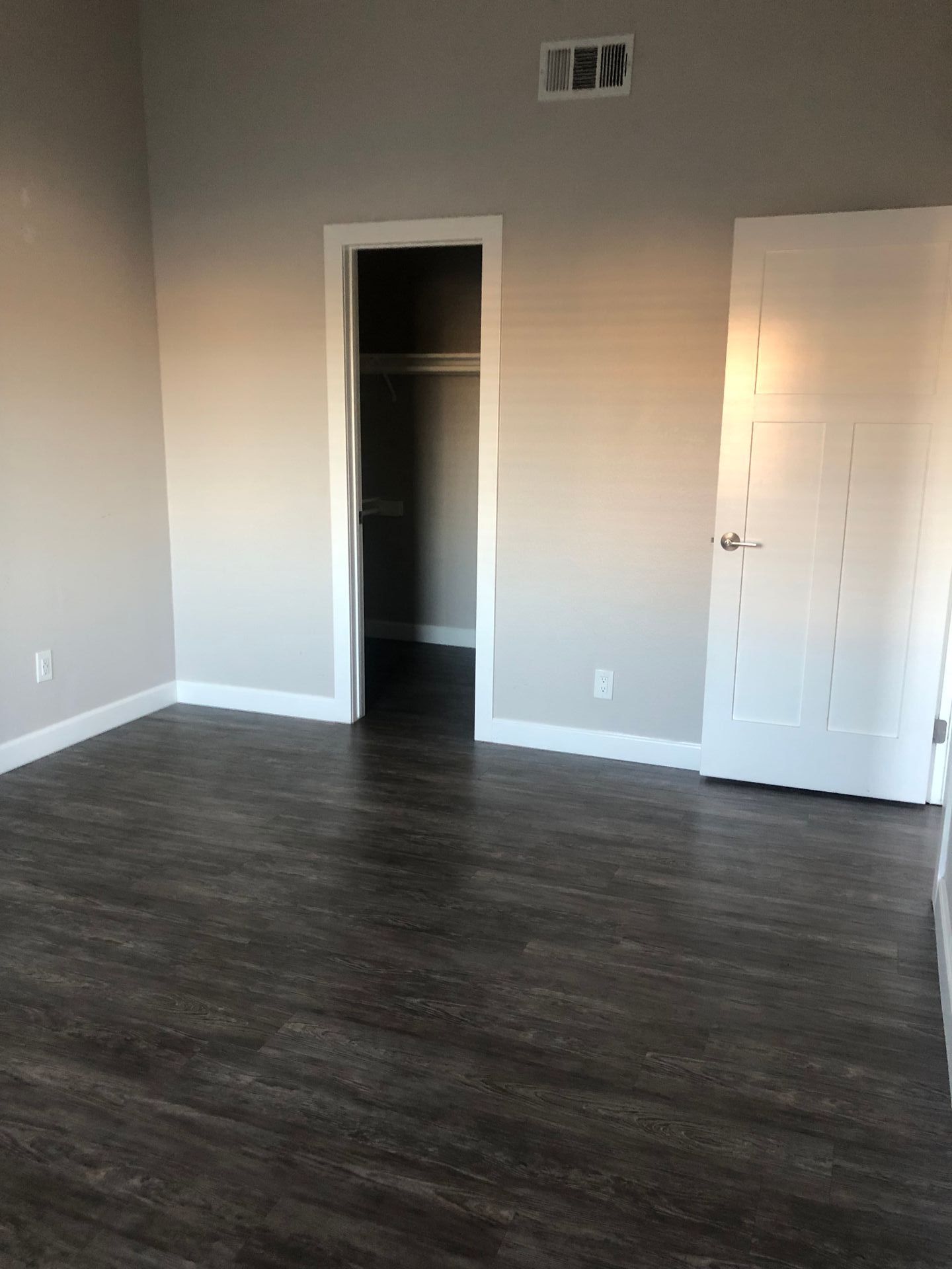 An empty room with hardwood floors and a door leading to a closet.