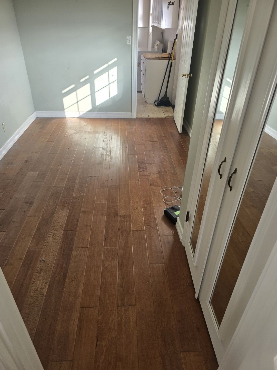 A room with hardwood floors and a mirrored wardrobe.