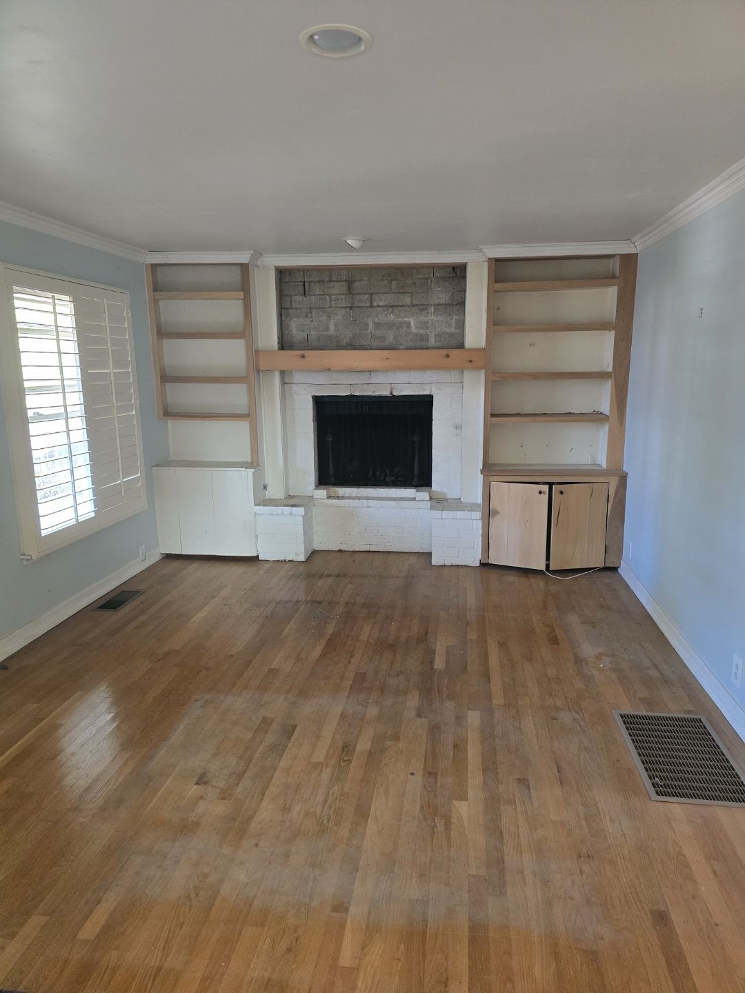 An empty living room with hardwood floors and a fireplace.