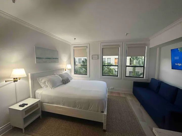 A hotel room with a king size bed and a blue couch.