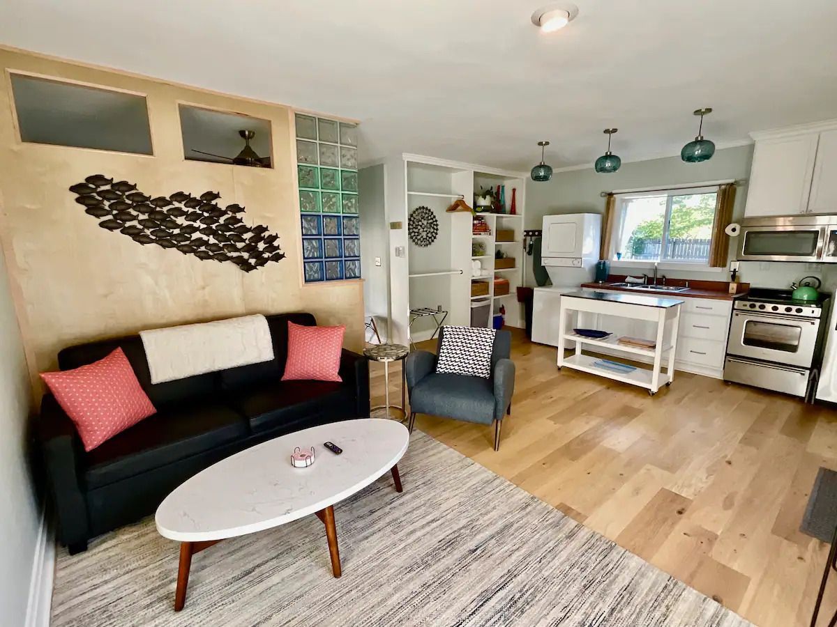 A living room with a couch , chair , coffee table and kitchen.