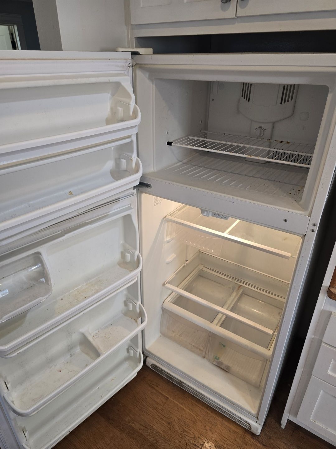 An empty refrigerator with the door open in a kitchen.