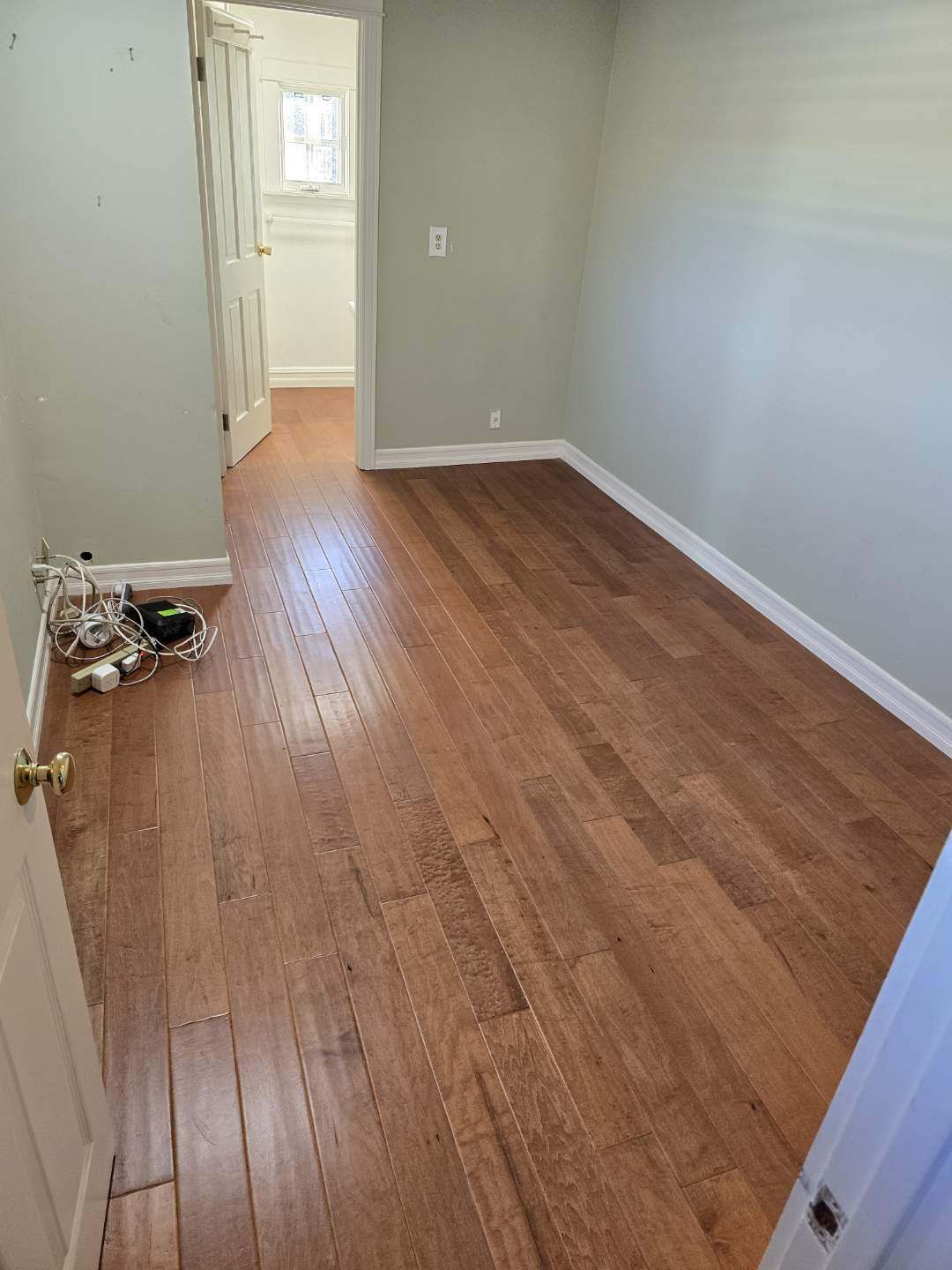 An empty room with hardwood floors and gray walls.