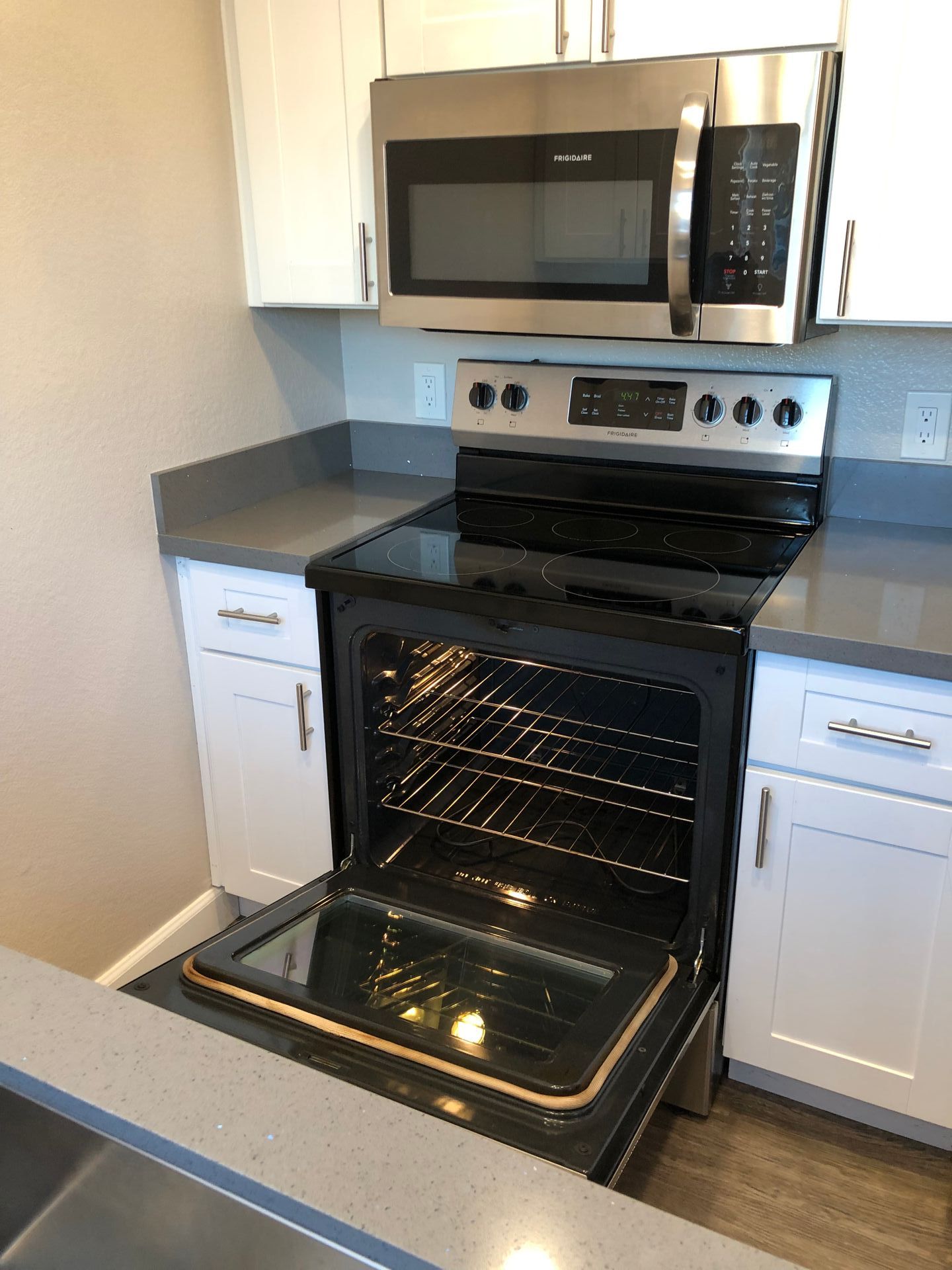 A kitchen with a stove and microwave with the oven open.