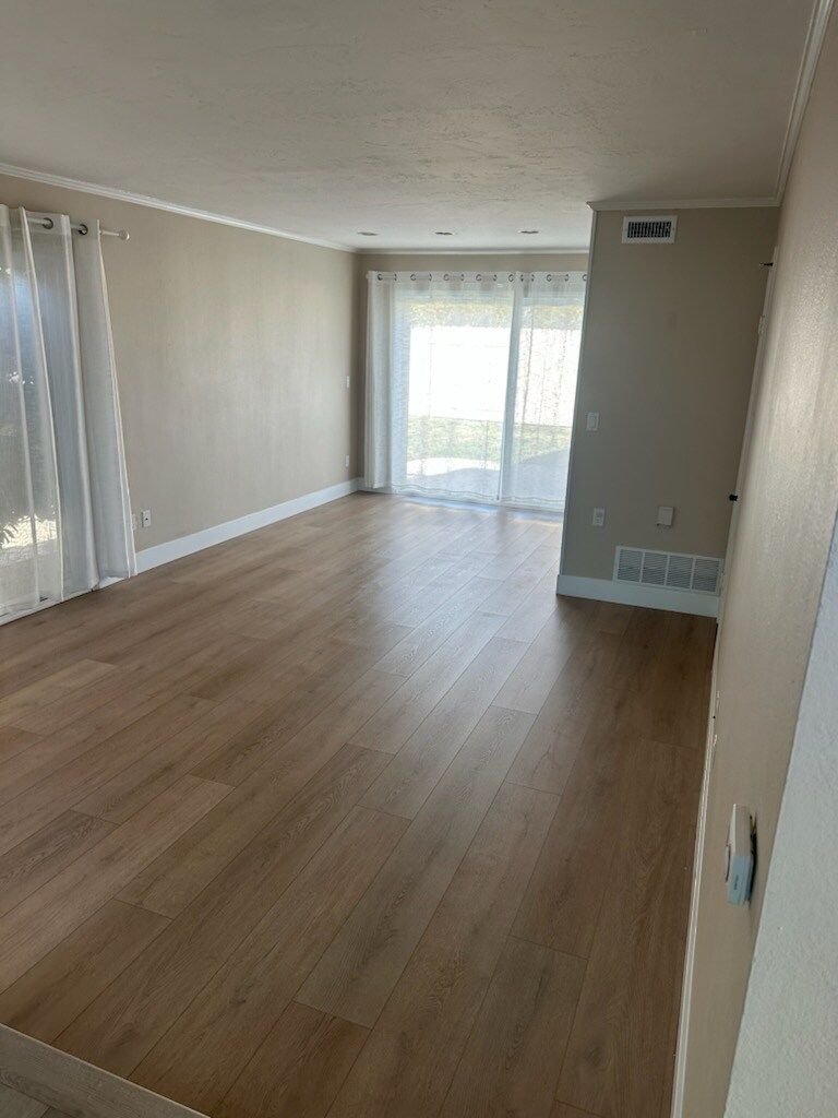 An empty living room with hardwood floors and sliding glass doors.