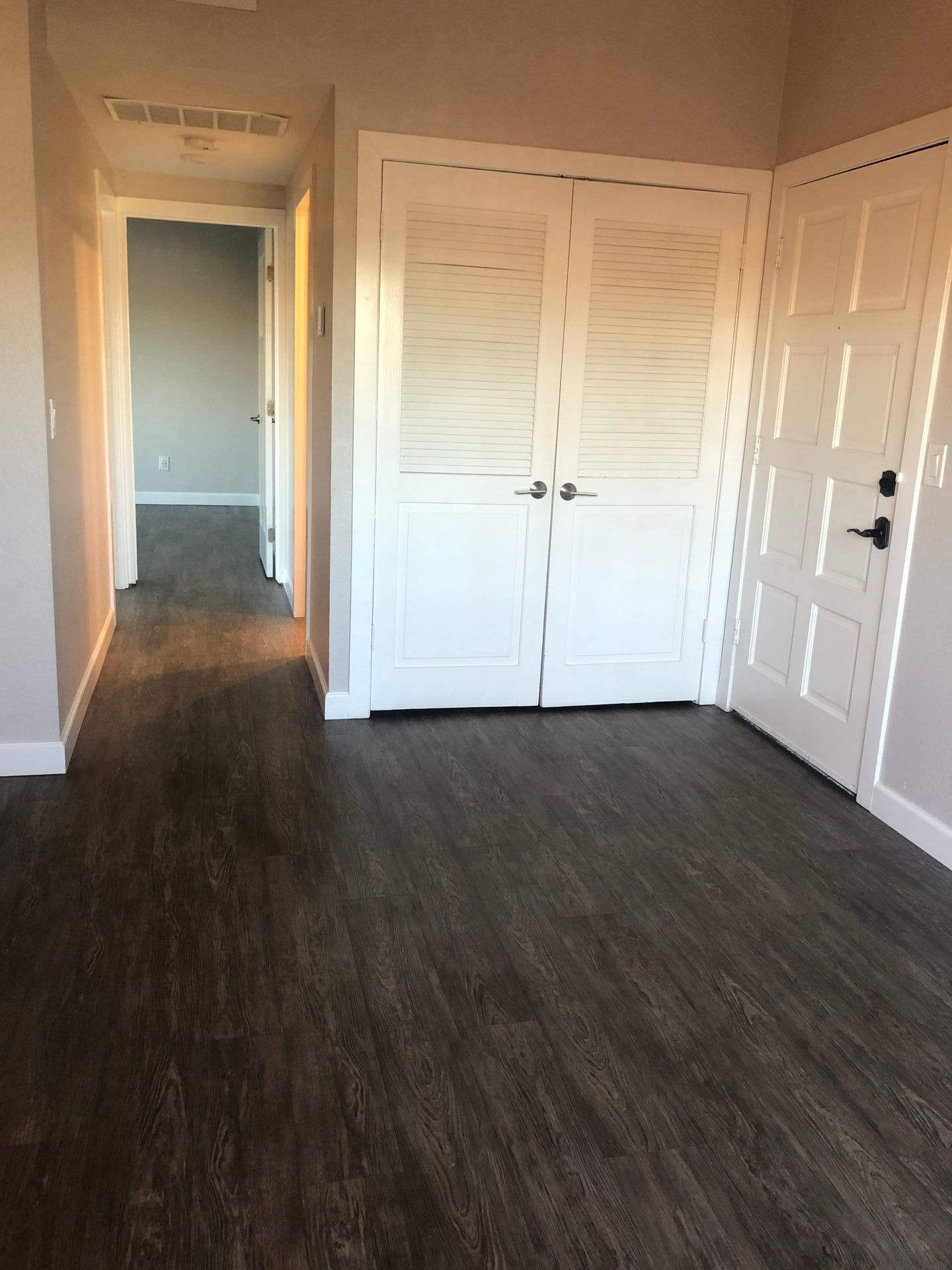 An empty room with a wooden floor and white doors.