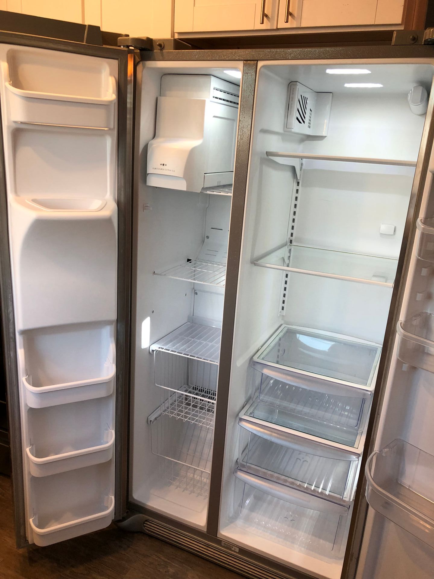 An empty refrigerator with the door open in a kitchen.