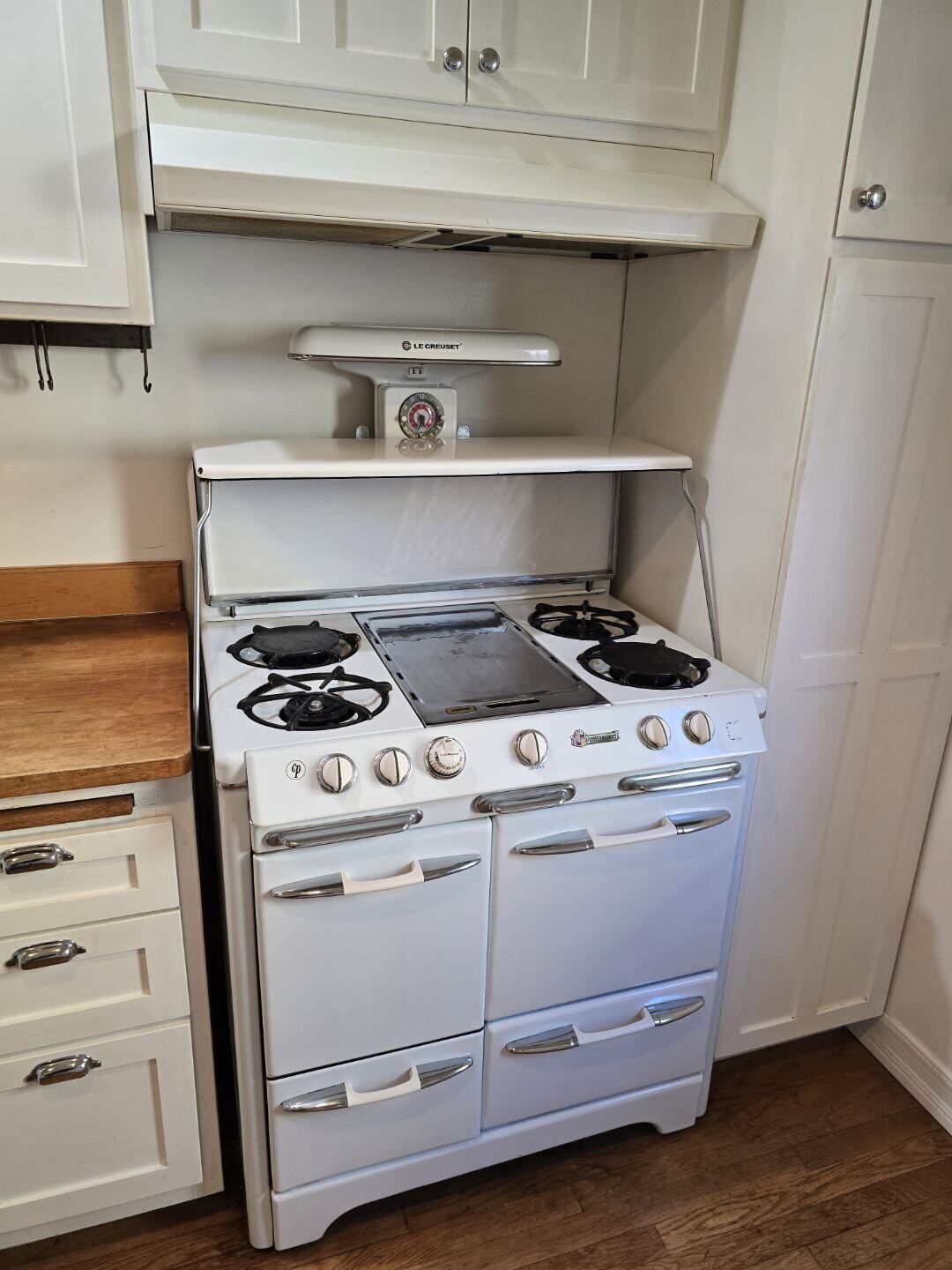 A white stove with a scale on top of it in a kitchen.