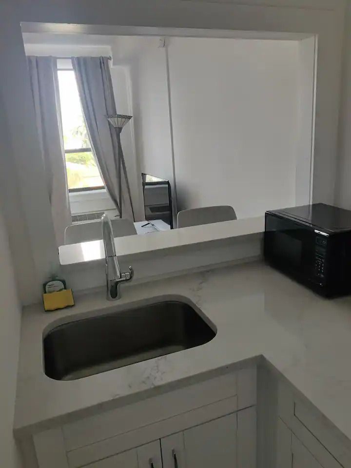 A kitchen with a sink , microwave , and window.