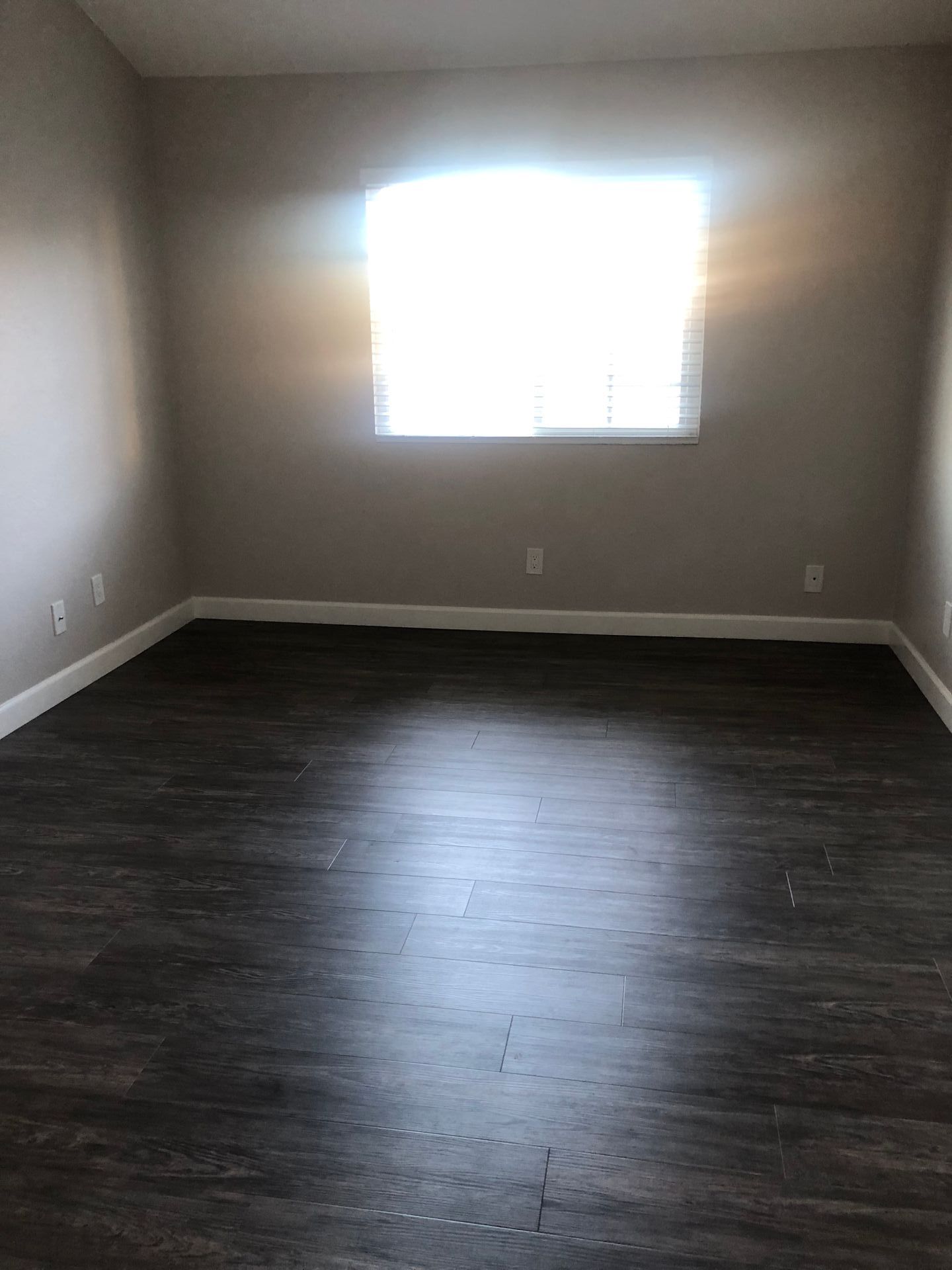 An empty living room with hardwood floors and a window.