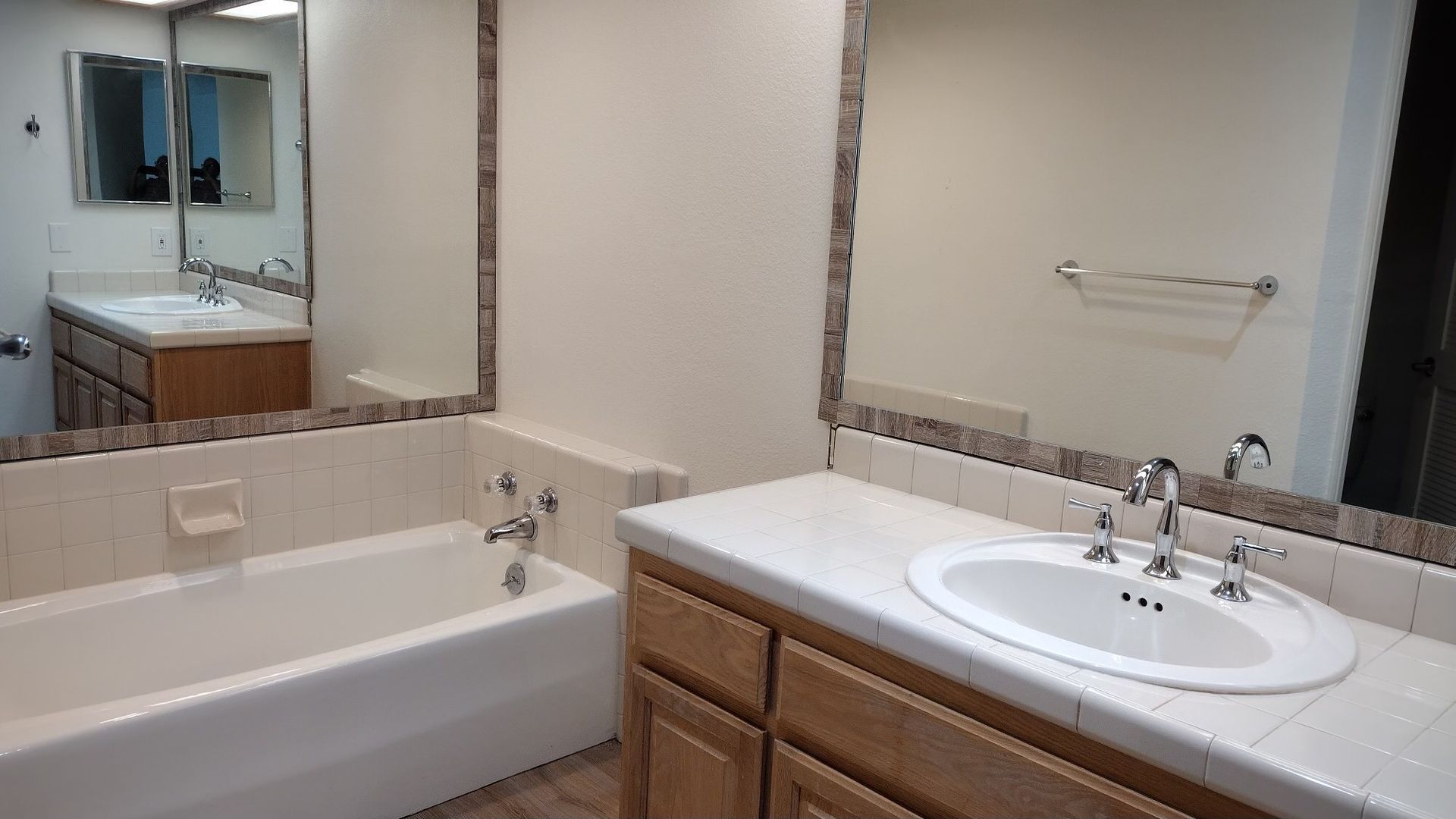 A bathroom with a tub , sink and mirror.