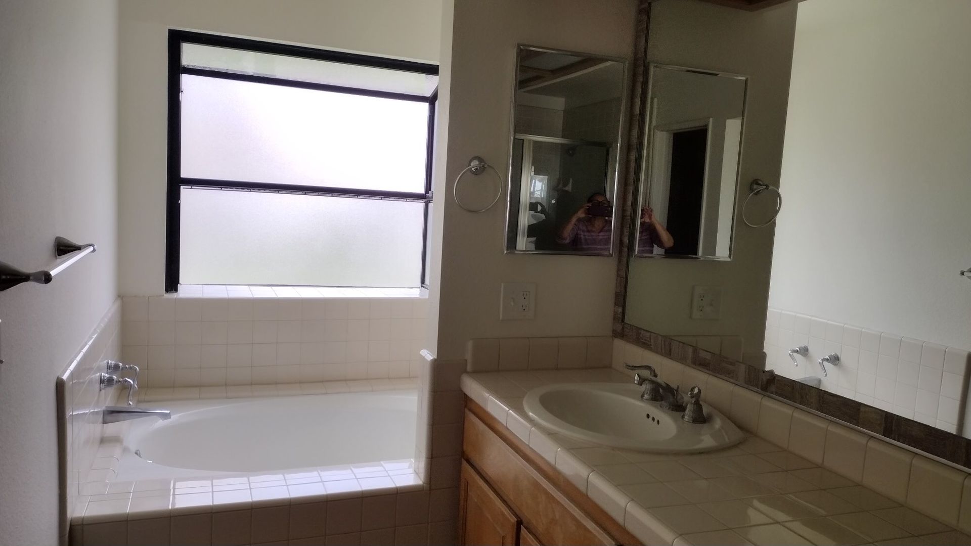 A bathroom with a tub , sink , mirror and window.