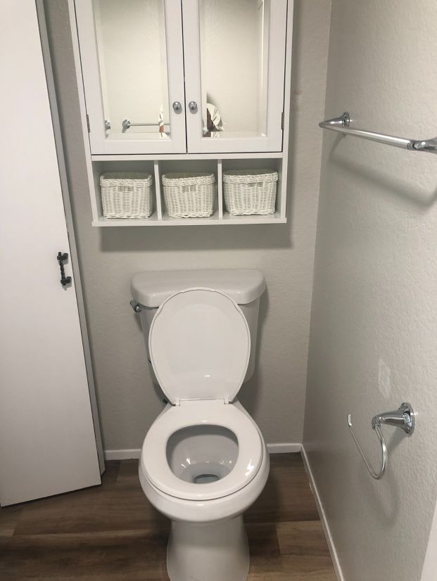 A bathroom with a toilet and a cabinet above it.