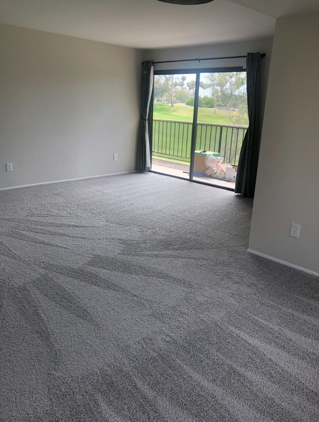 An empty living room with a sliding glass door and a balcony.