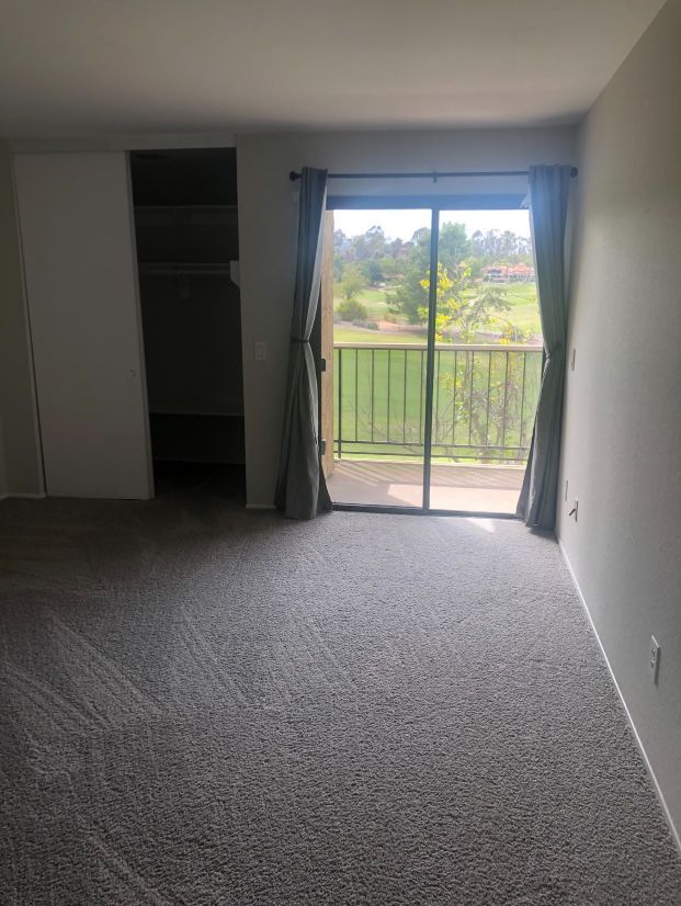 An empty room with a sliding glass door and a balcony.