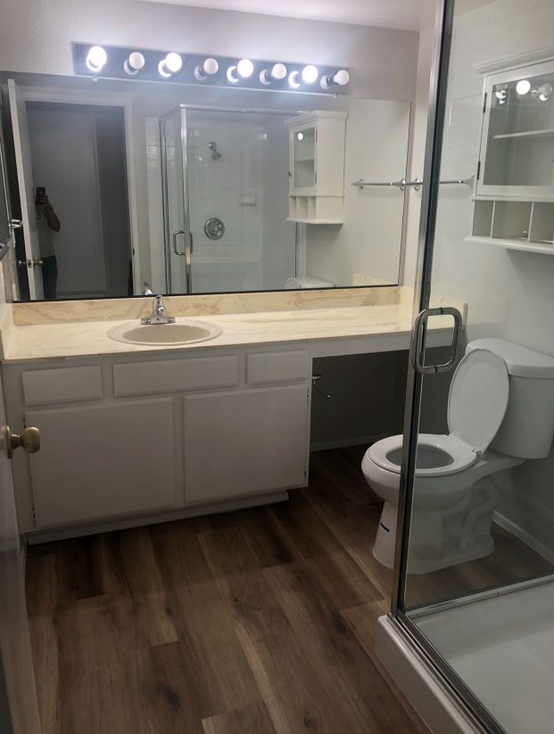 A bathroom with a toilet , sink and shower.
